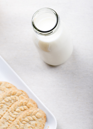 Milk bottle next to plate with cookies. Vertical studio shot.の写真素材