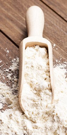 Wooden spoon with flour on wooden table. Vertical studio shot.の写真素材