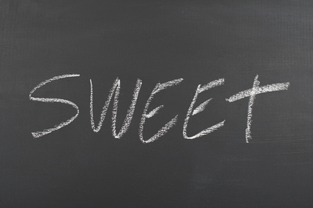 Sweet written with chalk on blackboard.の写真素材