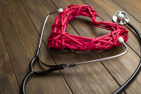 Close-up of creative composition made with big red mockup heart and stethoscope on wooden background.の写真素材