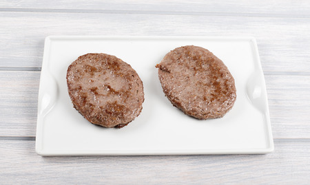 Burgers on white plate on wooden table. Food.