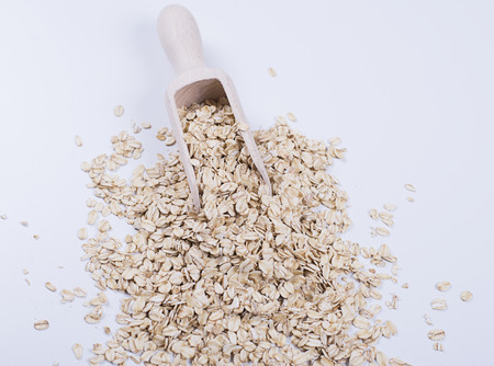 Oat flakes next to wooden spoon on white background. Isolated.の写真素材