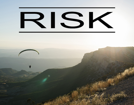 Background of mountain landscape at sunset with person doing paragliding, with the word Risk written above. Concept Advertising.の写真素材