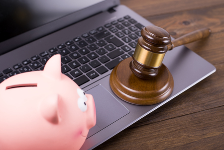 Judge gavel on laptop next to piggy bank. Concept of online bank.の写真素材
