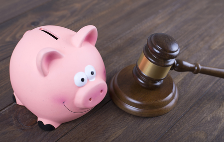 Judge gavel next to piggy bank on wooden table. Concept rights on savings.の写真素材