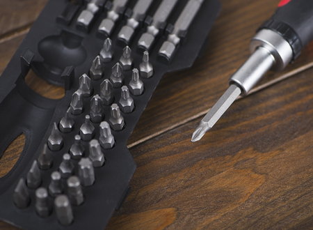 Close-up of set of heads for screwdriver on wooden background. Industry.