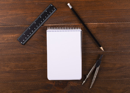 Notebook empty together pencil, compass and ruler on wooden table. Stationery. Concept of Back to...