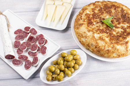 Omelette with cheese, sausage and olives on wooden table. Typical spanish food.の写真素材