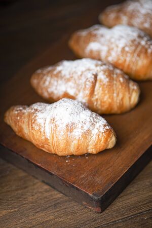 Croissants with sugar on top over wooden board.の写真素材