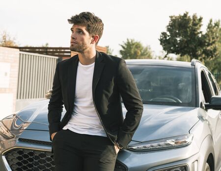 Close-up of attractive young man with beard in suit leaning on his car.suitの写真素材