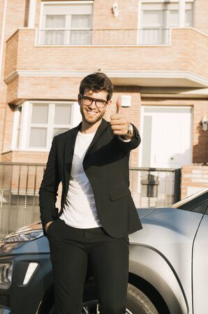 Close-up of attractive young man with beard and glasses in suit says ok with his hand to the camera.の写真素材