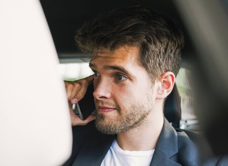 Young and attractive man with a beard speaks with his smartphone in a vehicle he does not drive. Businessの写真素材