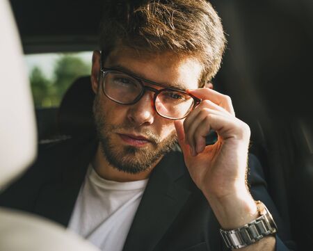 Attractive young man with beard and glasses with serious face looks at camera. Businessman.の写真素材
