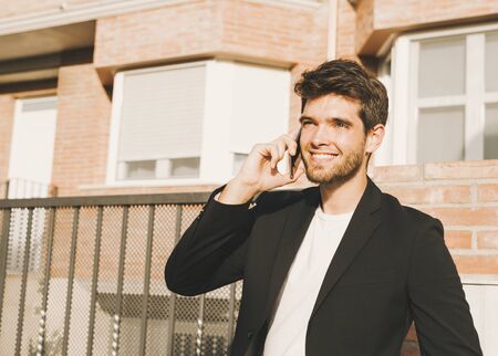 Close-up of attractive young man with beard in suit speaks on the phone and smiles.の写真素材