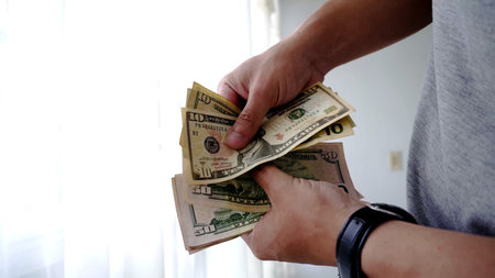 Man's hands counting one hundred dollar bills. Selective focus.の写真素材