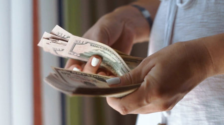 Counting Cash A CloseUp View of Dollar Bills Held in Hands for a Detailed Analysisの写真素材