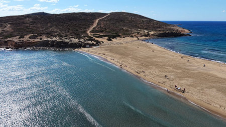 Aerial view of Prasonisi Beach at the southern tip of Rhodes, Greece, where the Aegean and Mediterranean seas meet. Clear turquoise water, sandy isthmus, people strolling and sunbathing, rugged headland and open blue horizon.の写真素材