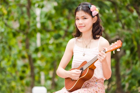 Asian girl with ukulele guitar outdoor in happy conceptの写真素材