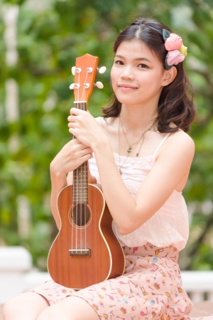 Asian girl with ukulele guitar outdoor in happy conceptの写真素材