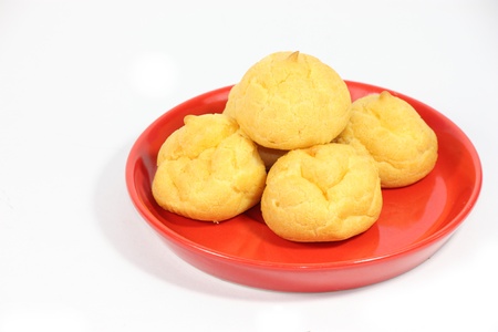 cream puff with filling on red plate isolated on white background