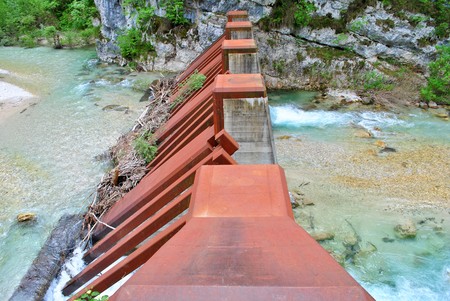 artificial dam in the river of grass surrounded by trees and forests in the valleys of Trentino south tyrolの写真素材