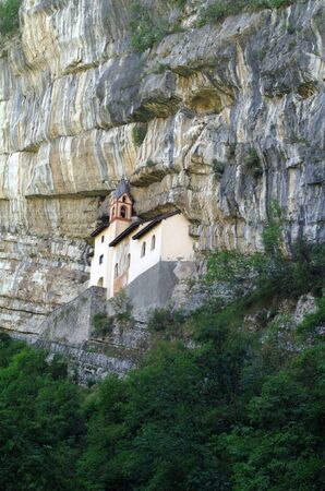 Catholic church  built on the rock wall surrounded by pine and larchの写真素材