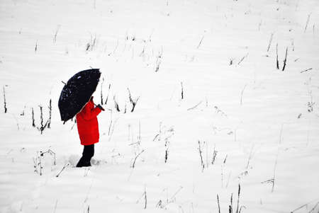 girl in the snow with a red cape and umbrellaの写真素材