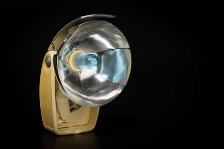 Old retro Camera Flash with reflector and blue bulb on black background