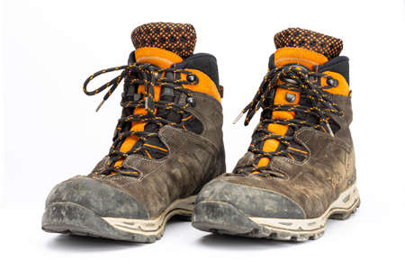 Pair of dirty brown/orange men's hiking boots with white background. Front view, landscape format.の写真素材