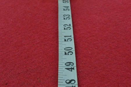 White tape measure on a red background with the numbersの写真素材
