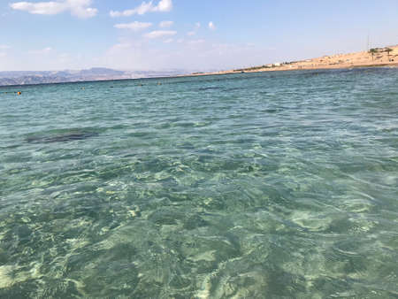 The sea in a light blue nearby is land in sight with brown sand