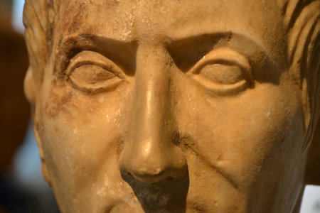 This is a close-up of a Roman marble bust, of the emperor Trajan. The statue has a strong brow line...