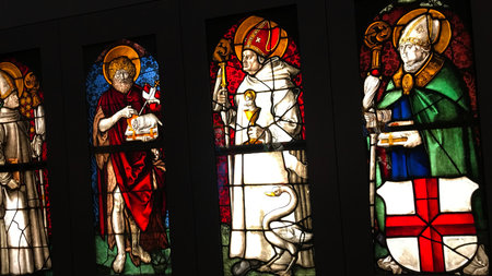 These four vibrant stained glass panels depict religious figures. One figure wears a white robe and...