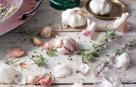 Garlic with Rosemary in an old rusty pot placed on a white farmhouse wooden table , with room for textの写真素材