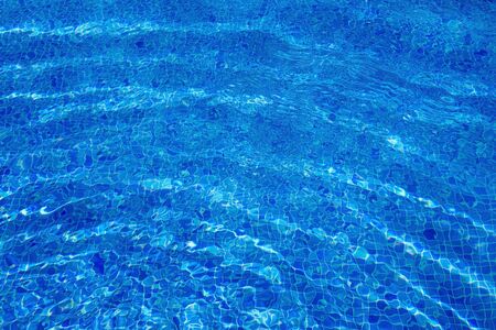 background of a blue tiled pool with clear cool rippling water