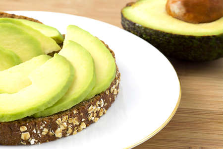 Avocado on toast placed on a white plate , Sliced on toast with a selecitve focus. half an avocado...