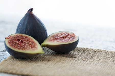 atmospheric food background concept of fresh figs whole and sliced selective forcus on a faded white background with right hand side copy spaceの写真素材