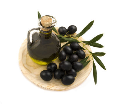 over head shot of a jar of fresh organic oil with picked  olives on a wooden plate isolated on a white backgroundの写真素材