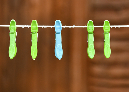 conceptual image of a rainy day, a line of wet pegs in the garden with raindrops bokeh background to accomated text overlay and copy spaceの写真素材