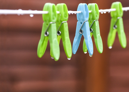 conceptual image of a rainy day  seletcive focus on a blue wet peg dripping raindrops in the yard bokeh background to accomated text overlay and copy spaceの写真素材