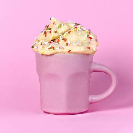 fun colored edible cookie dough in a pink cup with a matching pastel backgroundの写真素材