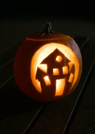 single carved pumpkin for halloween with a haunted house cut out vertical for posters and copy spaceの写真素材