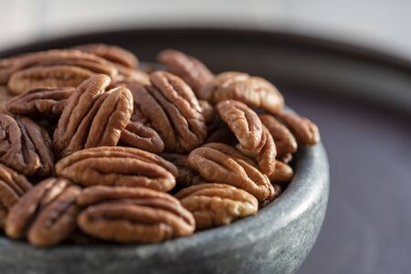 selective focus close up of a dish of ripe shelled pecan nuts in morning sunshine , blurred...