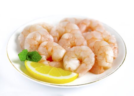 dish of cooked king prawns peeled on a white background close up with lemon and mintの写真素材