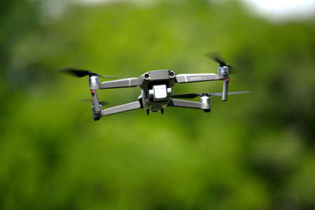 Modern drone with camera facing down flying and exploring nature on blurred background of green summer countrysideのeditorial素材