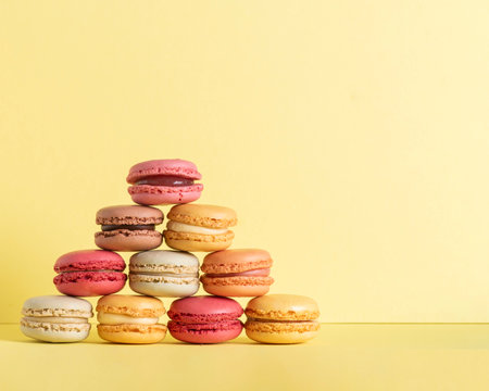 macaroons  fun colourful pyramid of pastel coloured  summer vibe soft yellow background n various flavors  with room fot copy spaceの写真素材