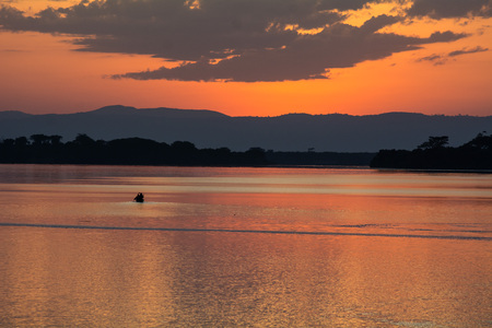 A small fisherman boat drives to a lake in Uganda and in the background is the sunset.の写真素材
