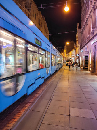 Blue Tram in the center of Zagreb Croatia with people at night. Illuminated historical buildings, cafes, restaurants and shopsのeditorial素材