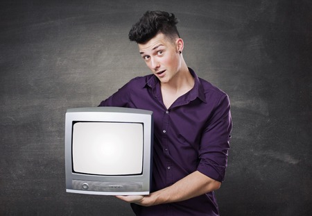 Happy man looking out of a television, holding it in his hands.の写真素材