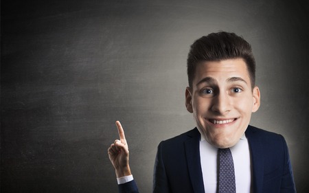 Funny businessman indicating with little arm e big head on blackboard backgorund.の写真素材